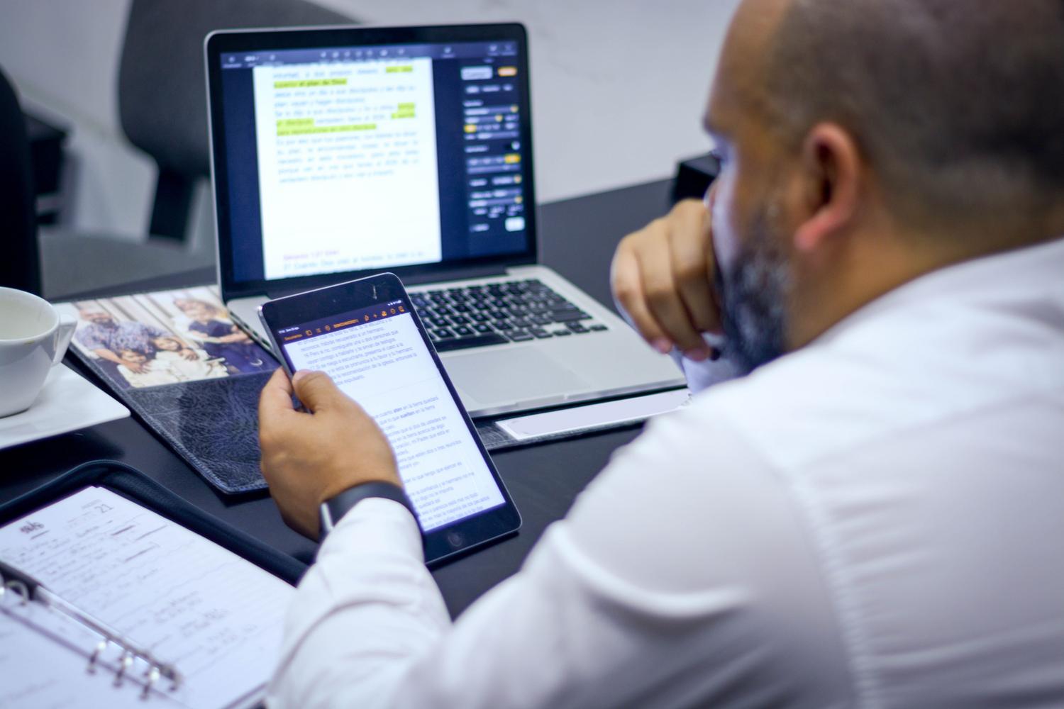 Profesional trabajando simultáneamente con un portátil y una tablet, representando la sincronización de los modos de concentración en todo el ecosistema de dispositivos.