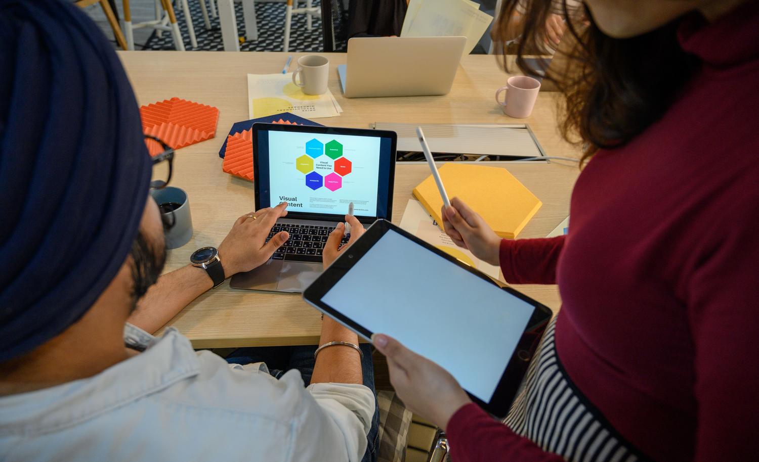 Profesionales colaborando en una oficina moderna con dispositivos digitales, representando la productividad y el trabajo en equipo.