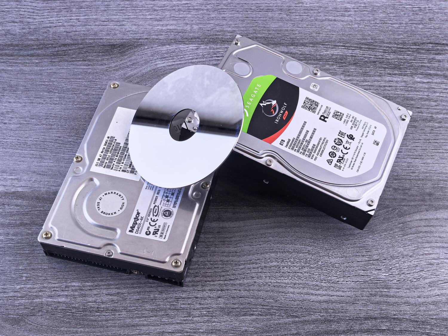 Dos discos duros mecánicos y un plato magnético sobre una superficie de madera Dos discos duros mecánicos y un plato magnético sobre una superficie de madera