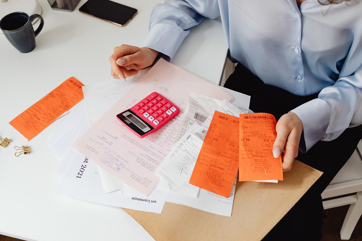 Mujer profesional revisando recibos y calculando gastos en un escritorio, ilustrando la tarea de gestión de facturación y contabilidad.