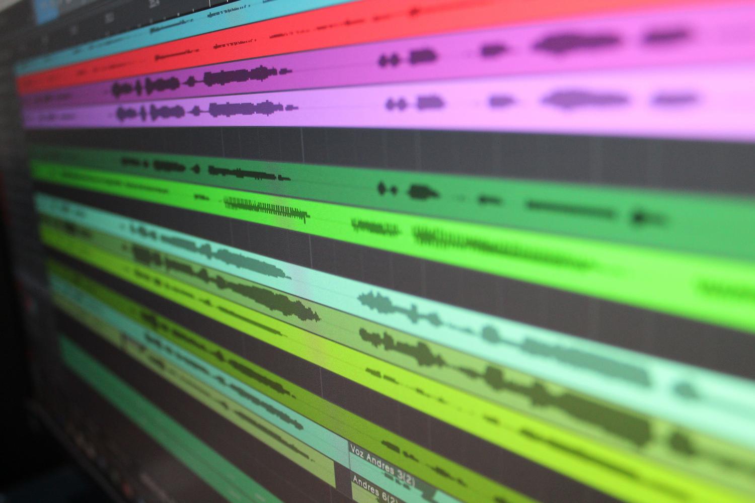Vista detallada de ondas de audio coloridas en la pantalla de un software de edición de sonido, representando la post-producción de audio.