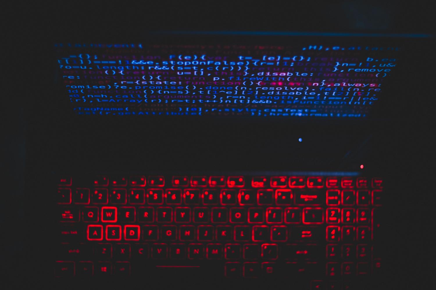 Primer plano de un teclado retroiluminado y código en pantalla, evocando la estética técnica de Linux.
