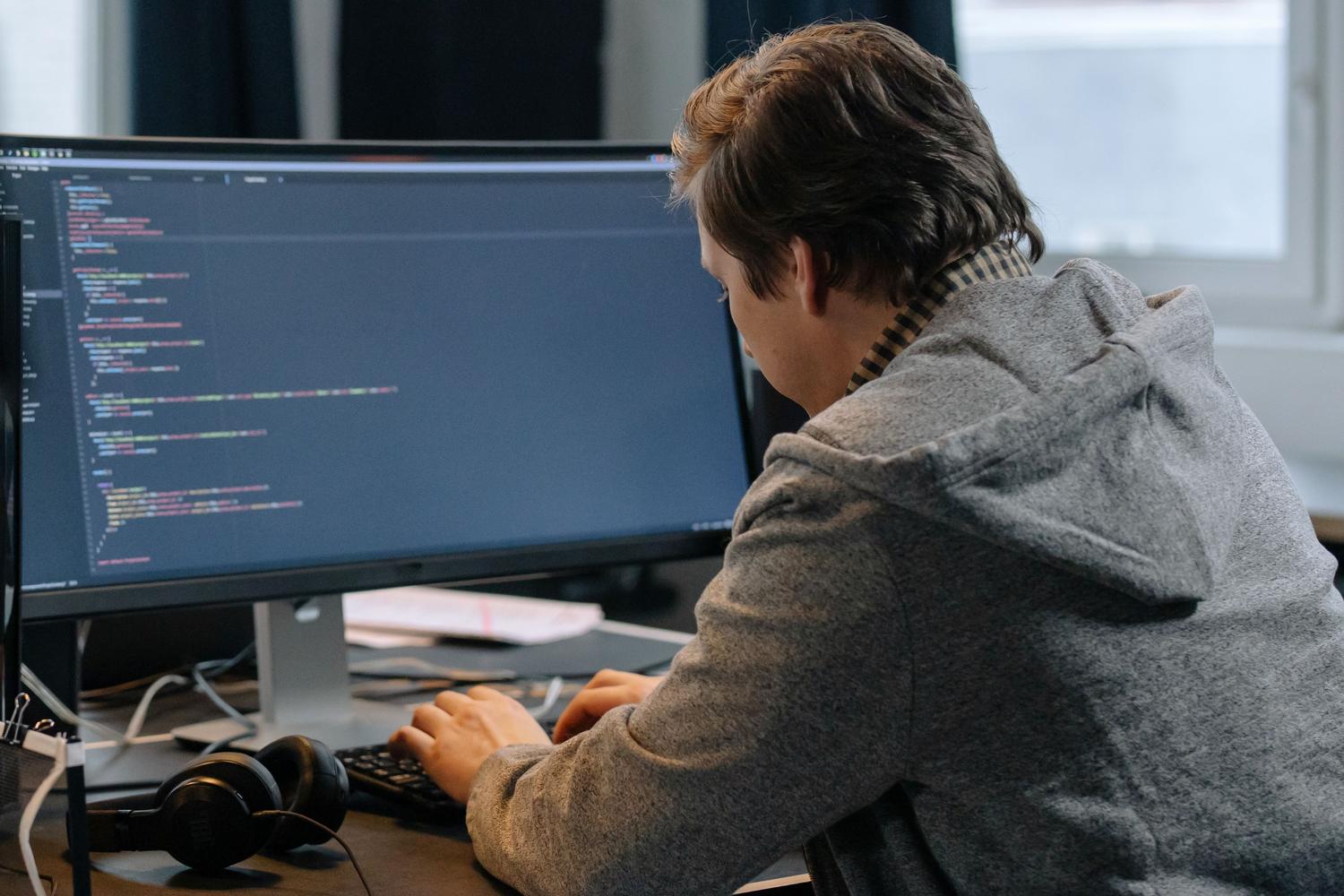 Desarrollador concentrado en su entorno de trabajo técnico con un monitor amplio.