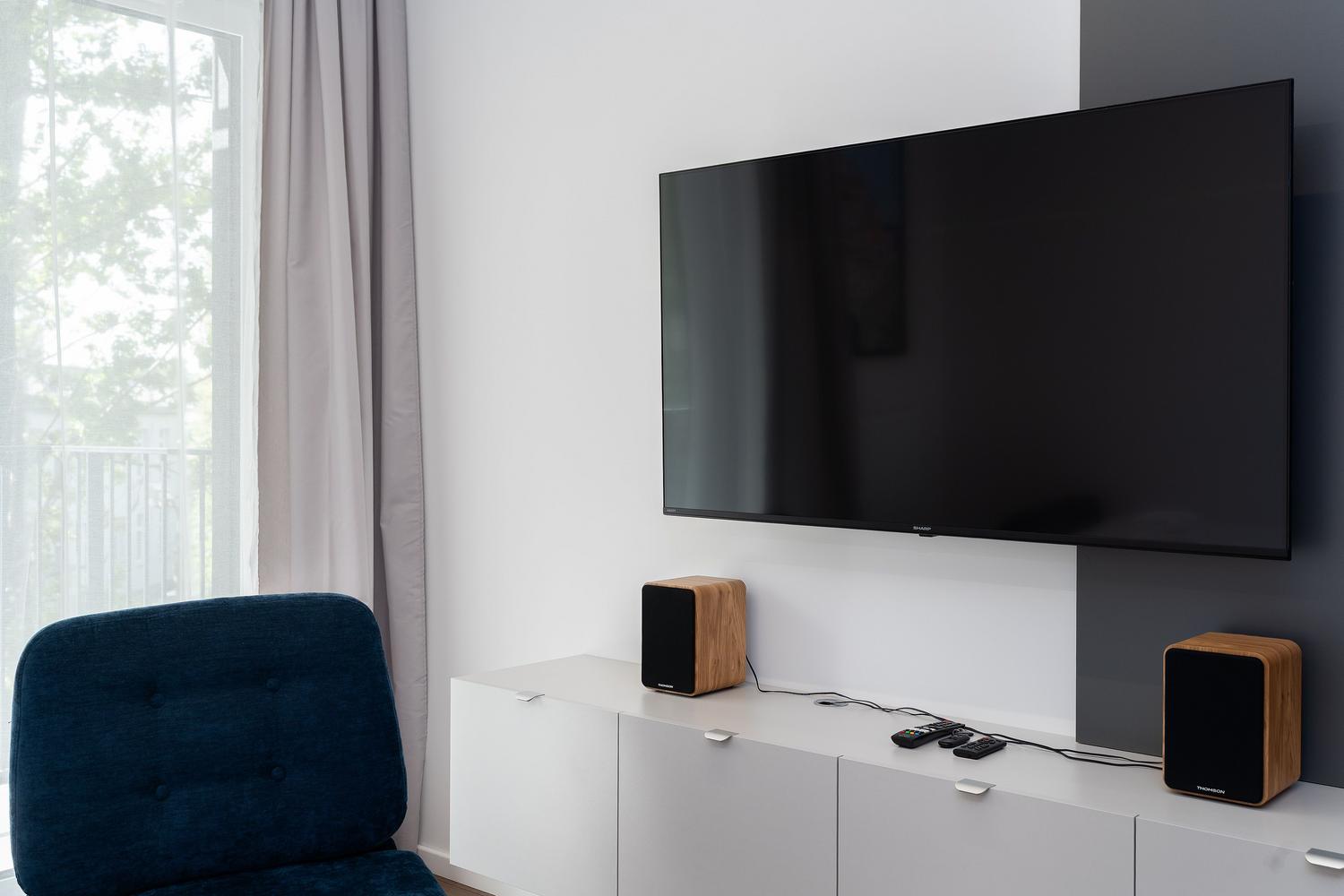 Salón moderno con televisor y altavoces elegantes, ideal para ilustrar la configuración de sonido en casa y el ajuste de barras de sonido.