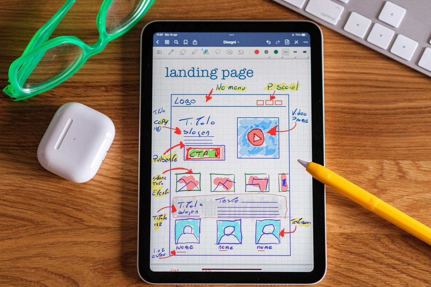 Vista cenital de una tableta digital mostrando el wireframe o boceto de una landing page, ilustrando la fase de planificación y diseño de una aplicación web.