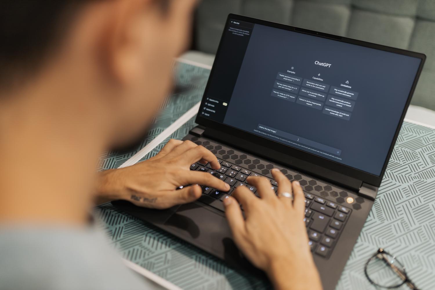 Persona concentrada programando un chatbot de inteligencia artificial en su ordenador portátil.