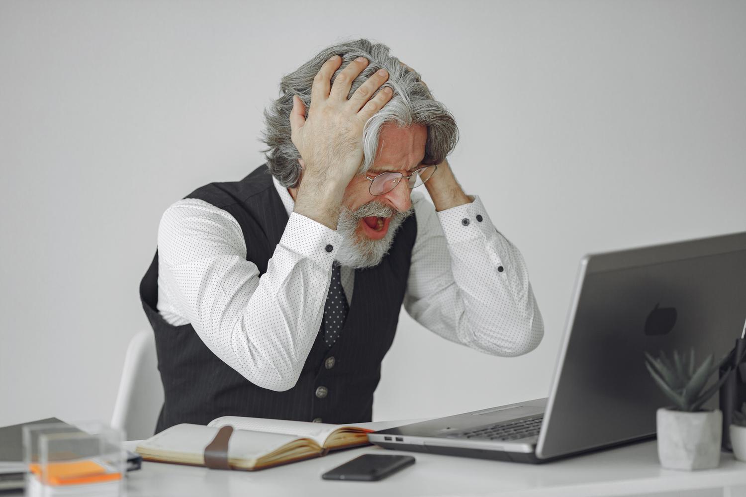Hombre frustrado frente a su ordenador portátil expresando descontento al no cumplir los requisitos del sistema