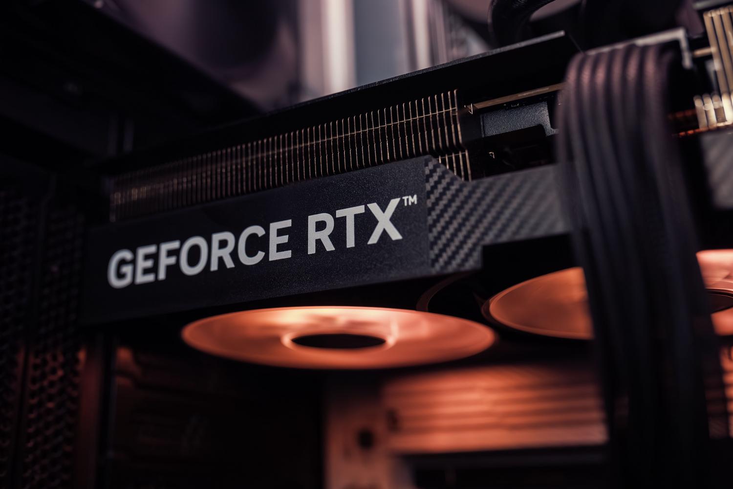 Primer plano de una tarjeta gráfica NVIDIA GeForce RTX instalada dentro de un ordenador gaming con iluminación ambiental. Primer plano de una tarjeta gráfica NVIDIA GeForce RTX instalada dentro de un ordenador gaming con iluminación ambiental.
