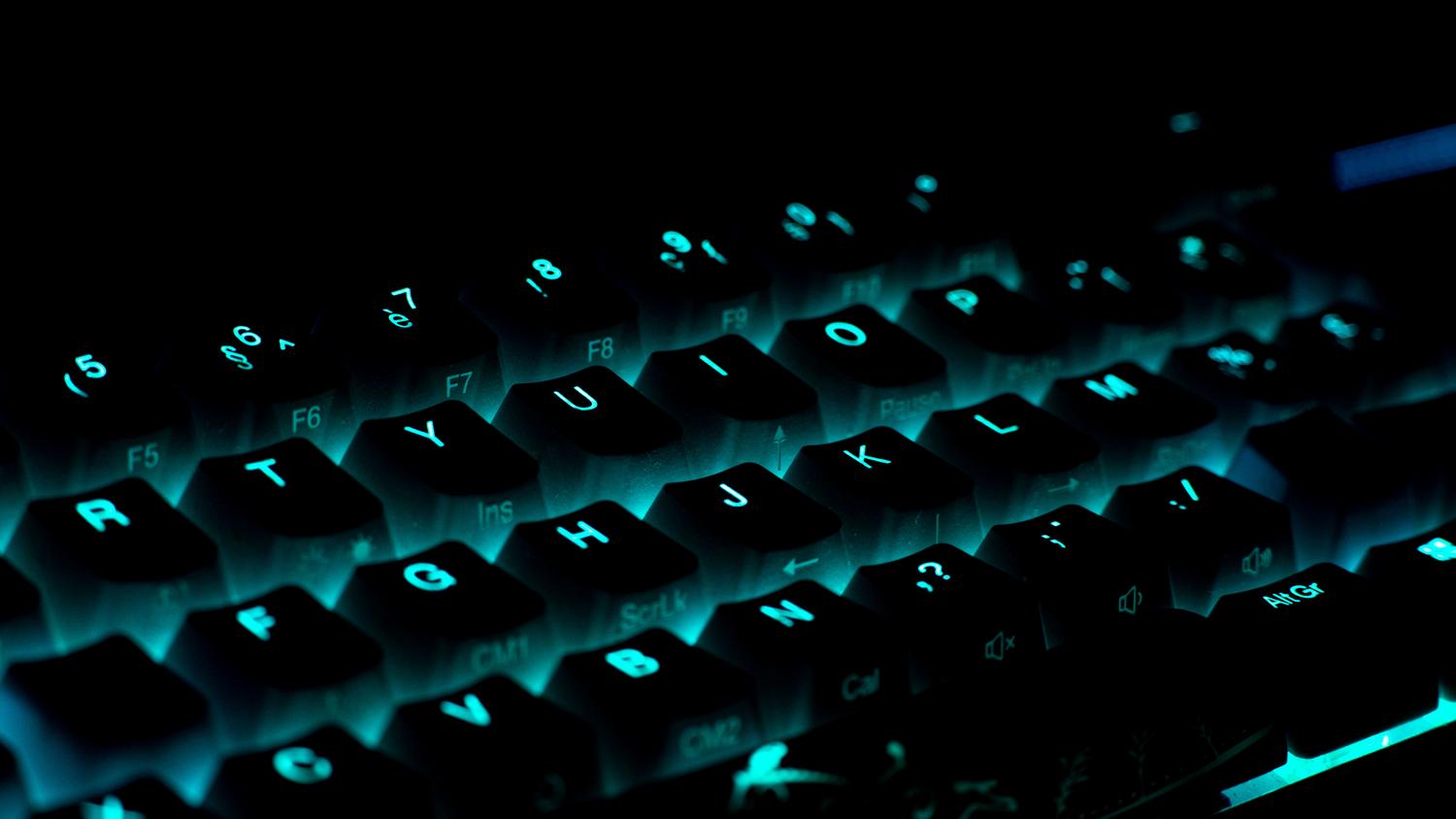 Teclado mecánico iluminado en un entorno oscuro, evocando la atmósfera de un desarrollador de software.