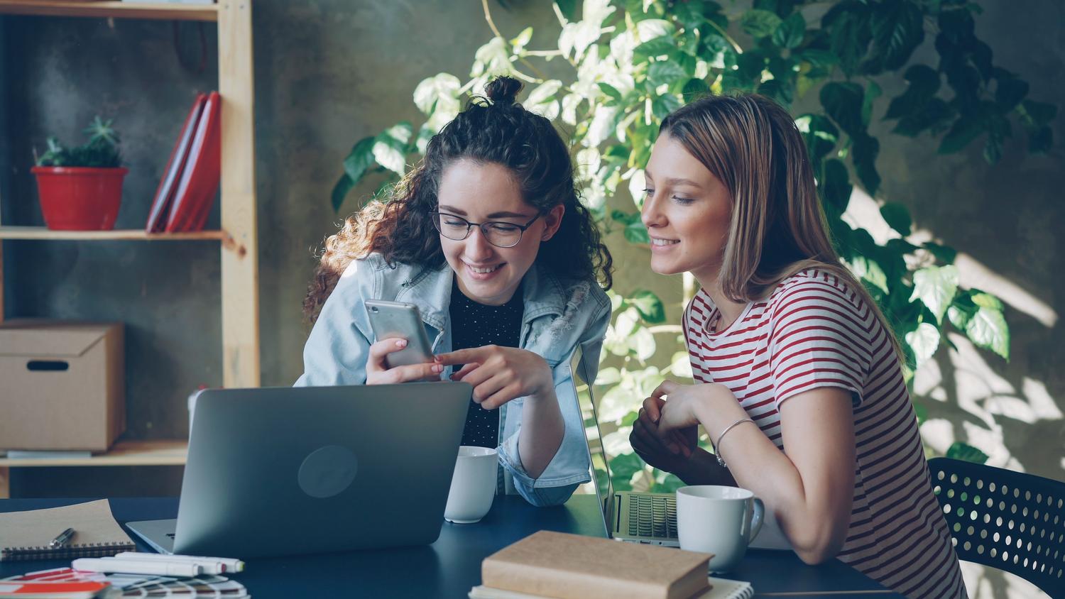 Colaboradores en una oficina moderna utilizando dispositivos móviles y laptops para el aprendizaje continuo.