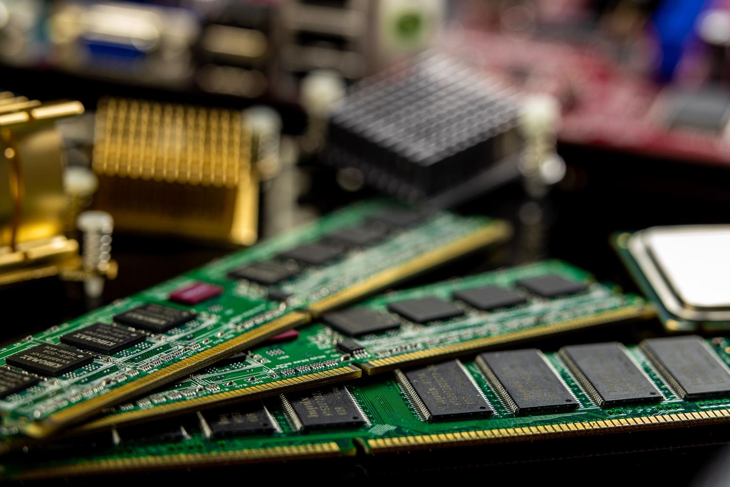 Fotografía macro de módulos de memoria RAM y un microprocesador instalados en una placa base verde.