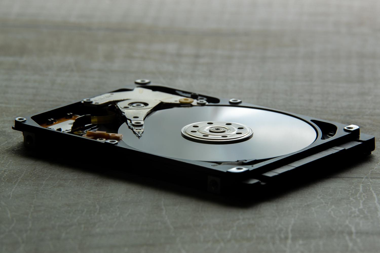Vista detallada del interior de un disco duro mecánico HDD, mostrando el plato magnético y el brazo actuador.