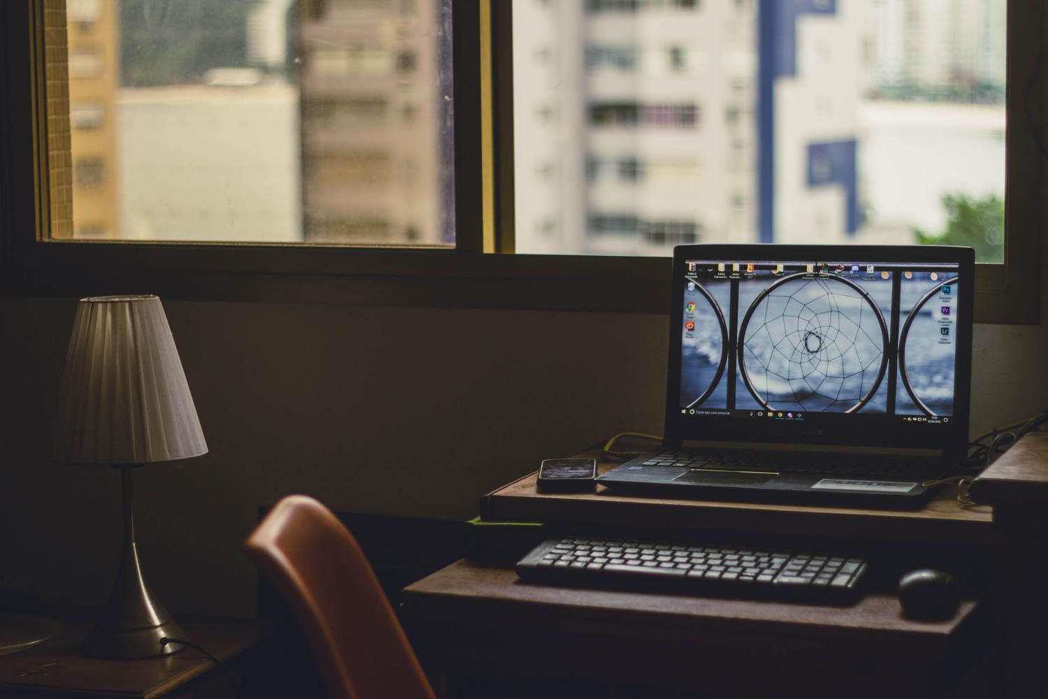 Espacio de trabajo minimalista con un portátil organizado sobre un soporte de madera, transmitiendo orden y optimización.