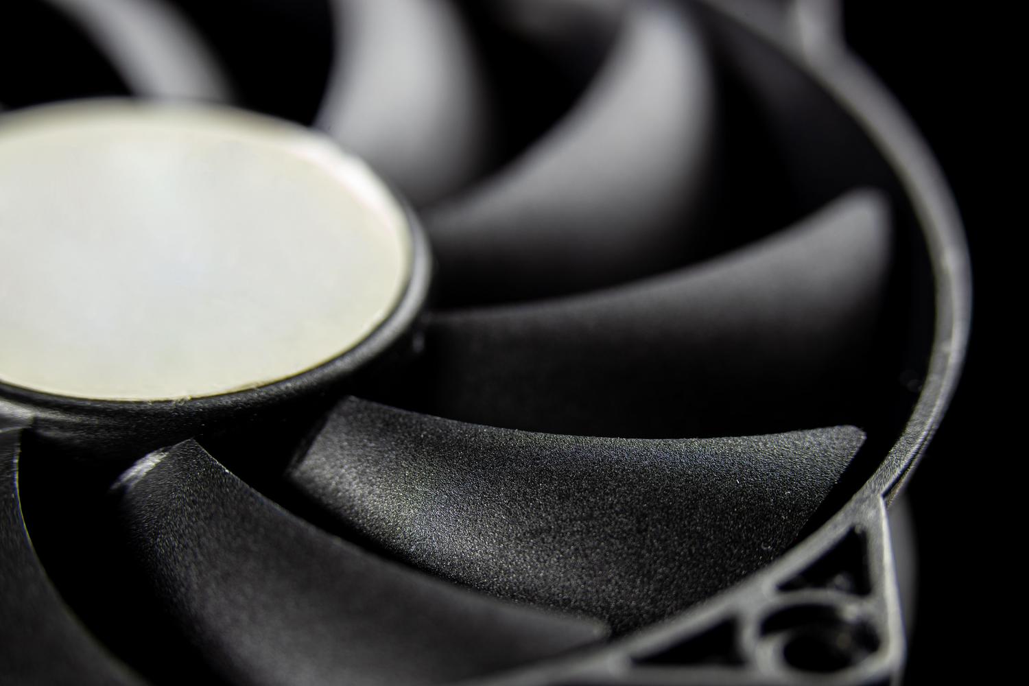 Fotografía macro de las aspas de un ventilador de refrigeración para ordenador en tonos oscuros, destacando la importancia de la gestión térmica.