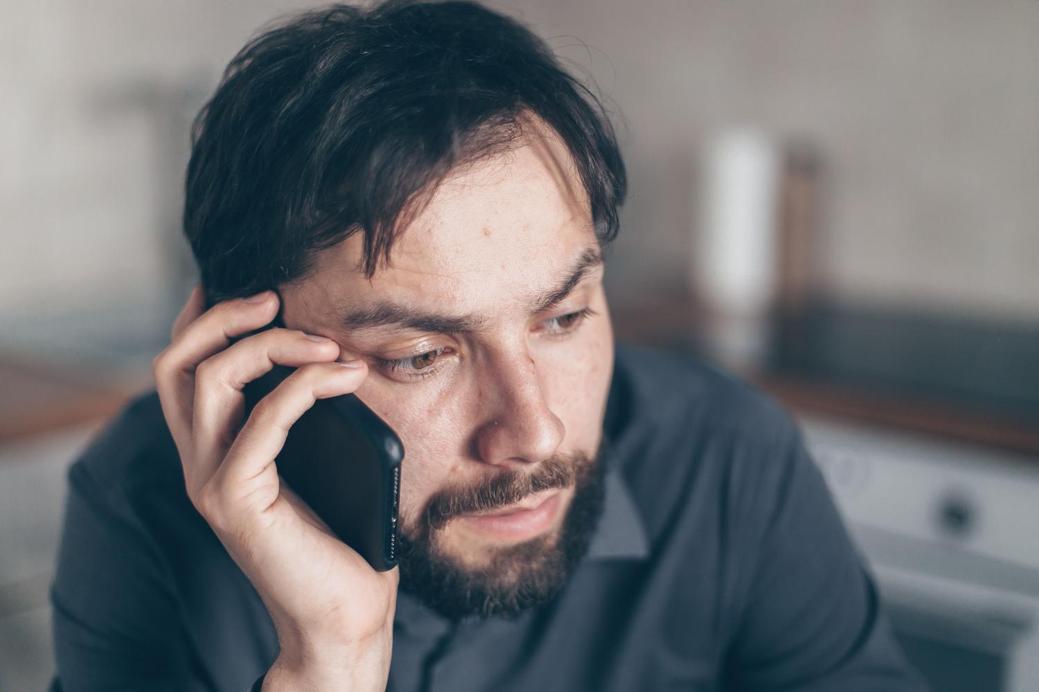 Hombre con expresión de preocupación y frustración utilizando su teléfono móvil, representando la molestia de perderse por un GPS impreciso.