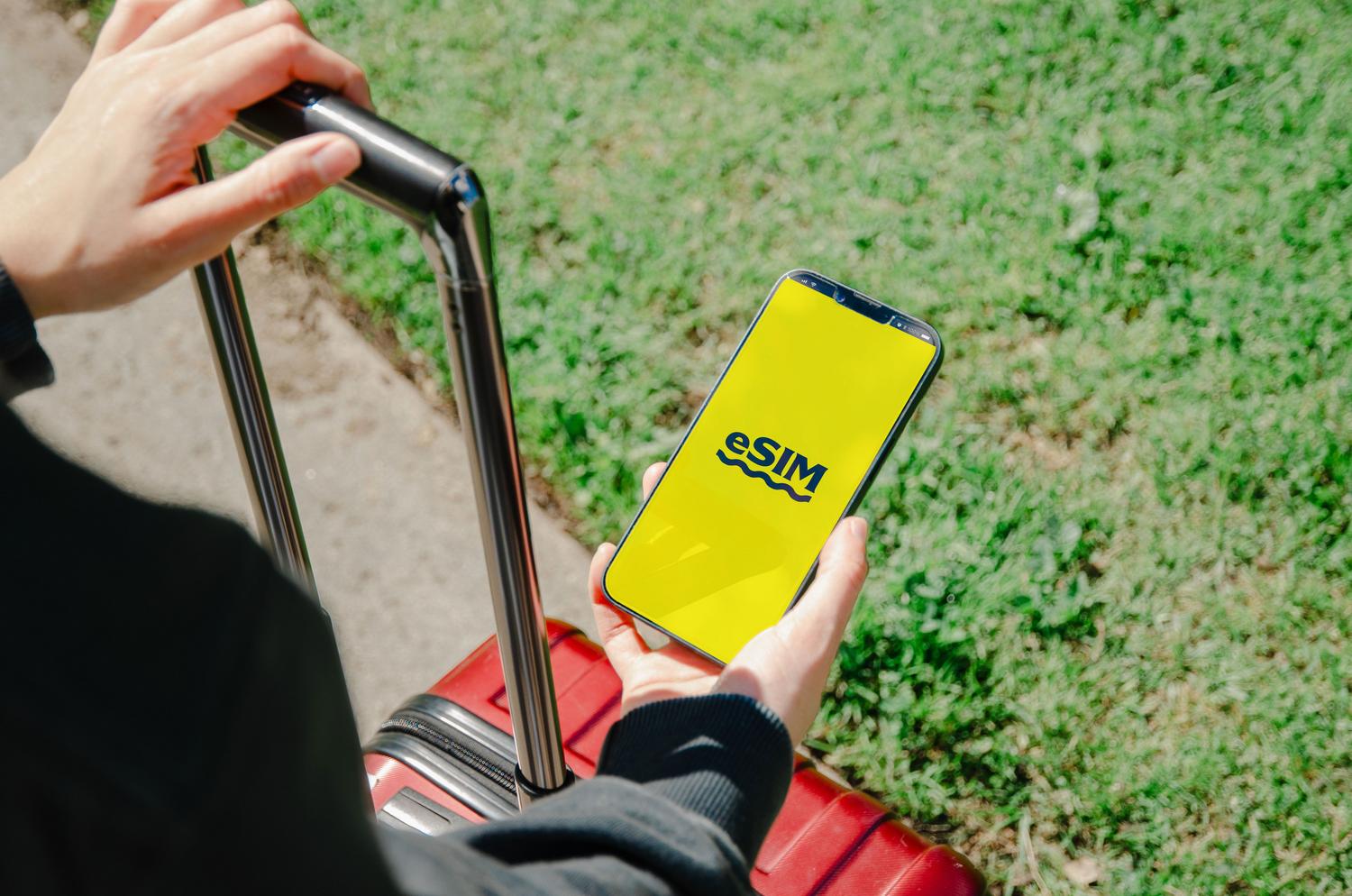 Persona sosteniendo un smartphone que muestra una aplicación de eSIM, ideal para ilustrar la sección de tarjetas SIM virtuales.