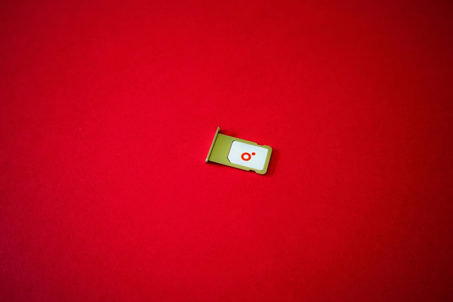 Bandeja de tarjeta SIM sobre un fondo rojo vibrante, excelente como imagen de cabecera por su impacto visual y espacio para texto.
