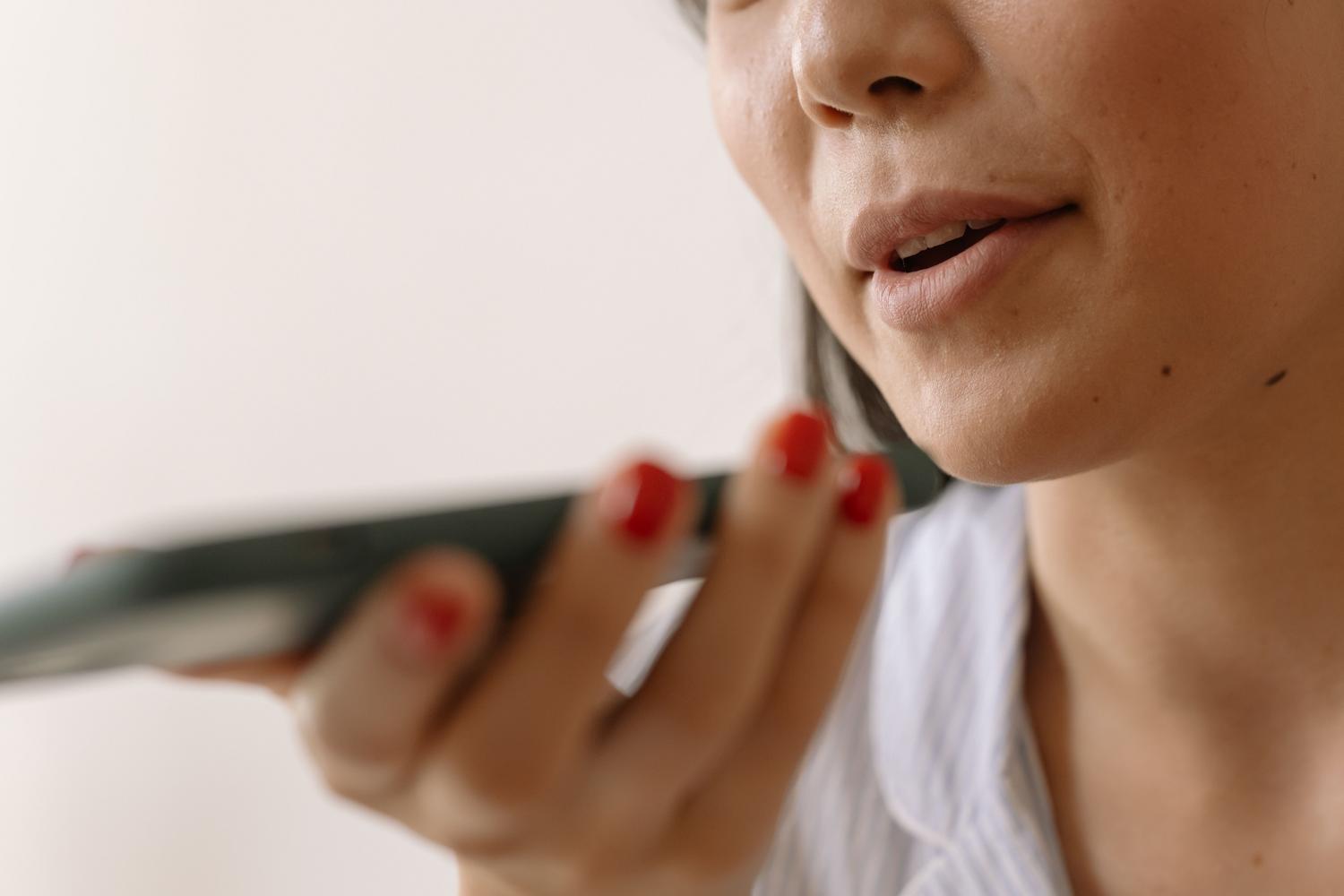 Primer plano de una persona hablando al micrófono de un smartphone para realizar una prueba de sonido.