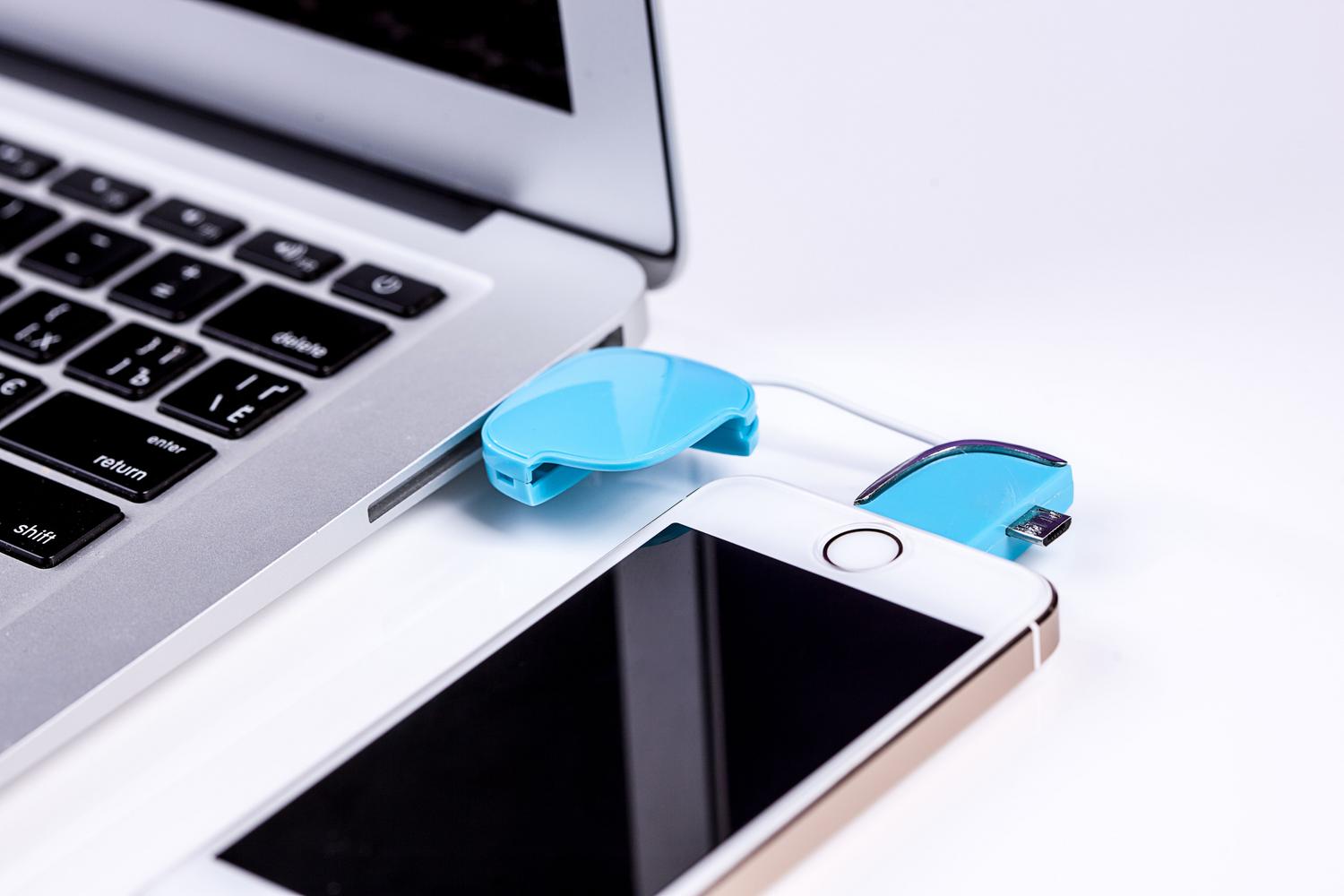 Primer plano de un smartphone conectado a un ordenador portátil mediante un cable USB para la transferencia de datos y recuperación del sistema.