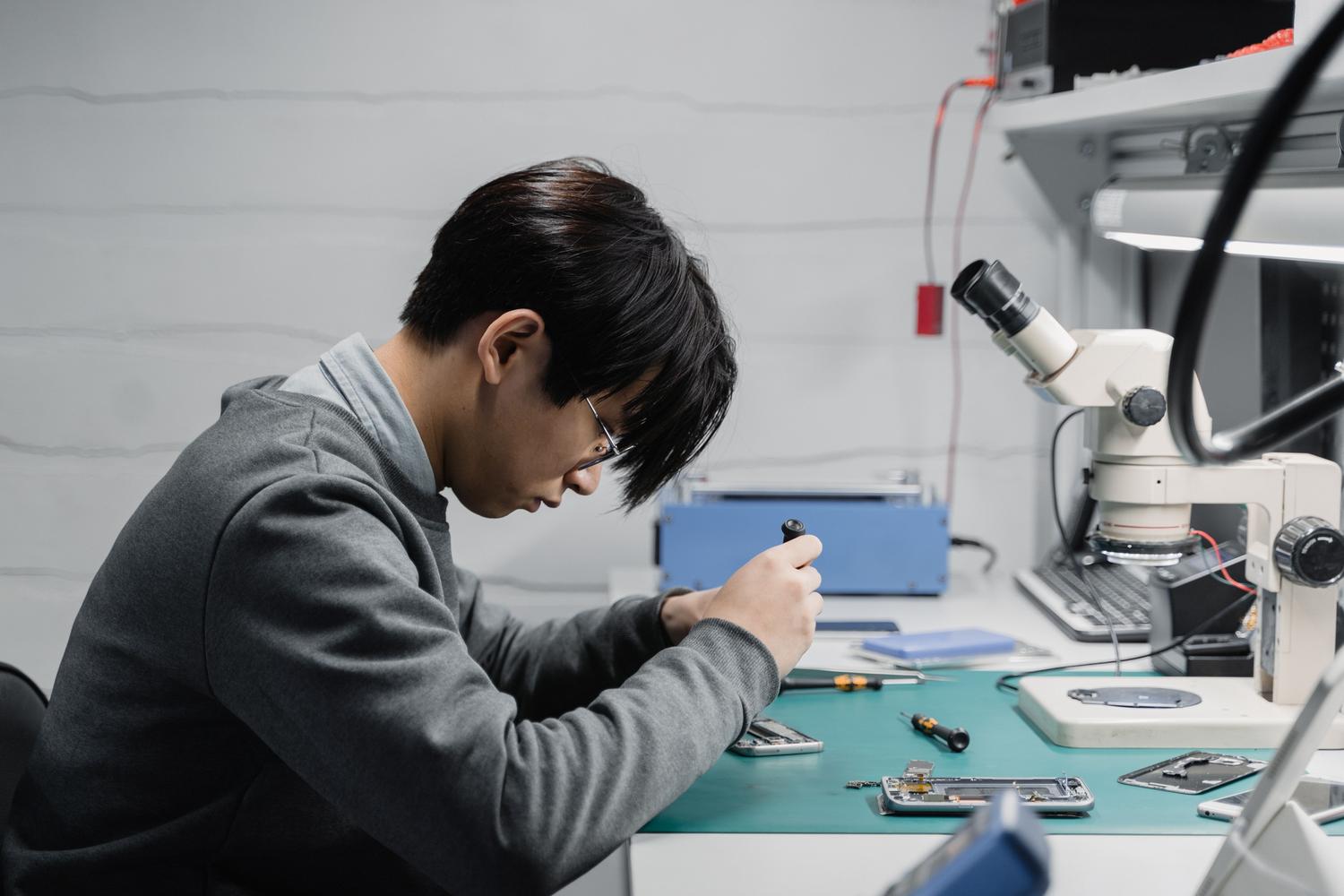 Técnico profesional reparando dispositivos móviles en un laboratorio, representando la opción de acudir a un servicio técnico autorizado de Apple.