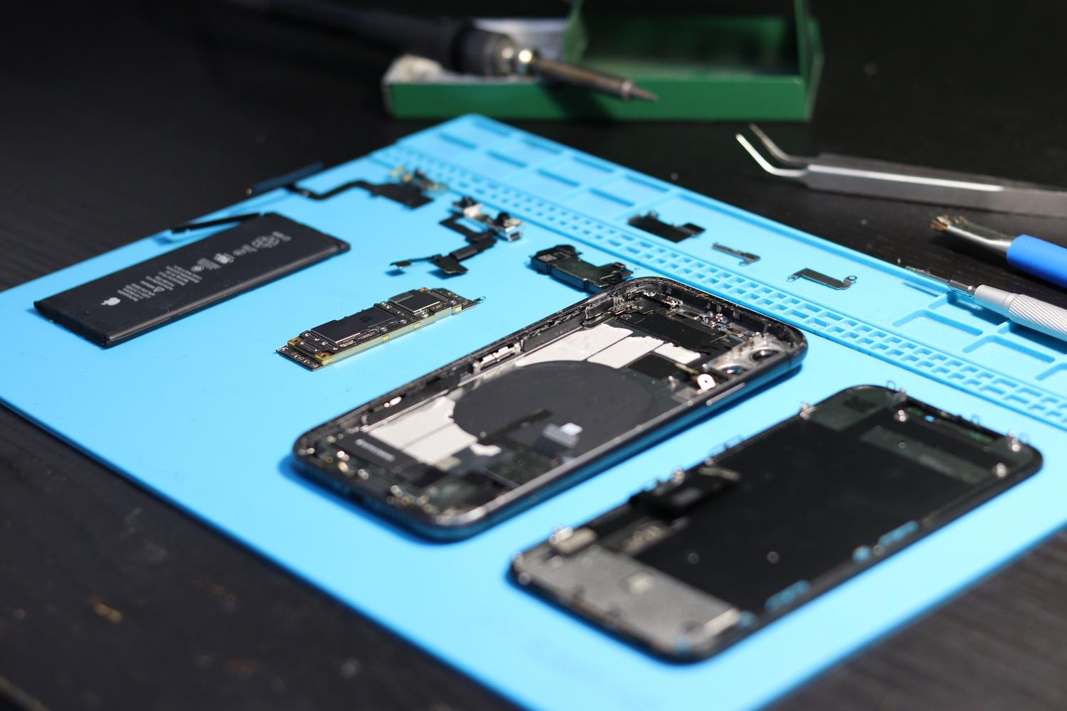 Un smartphone desensamblado sobre una mesa de trabajo con herramientas de precisión para su reparación.