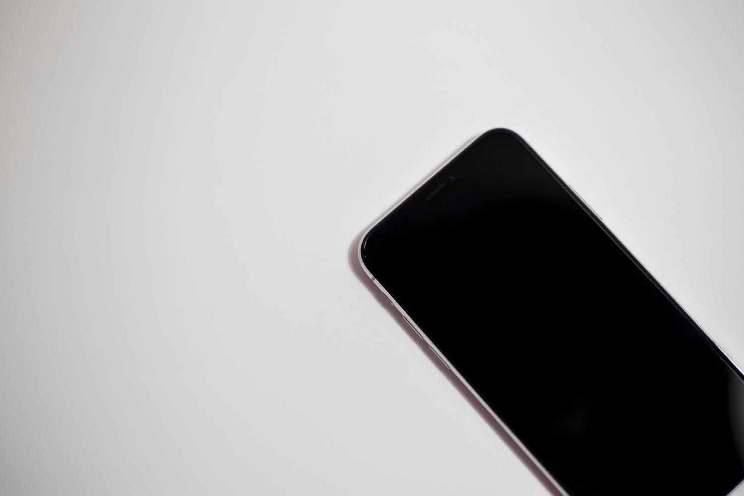 Primer plano de un smartphone con la pantalla totalmente negra sobre un fondo blanco, ideal para ilustrar el problema principal.