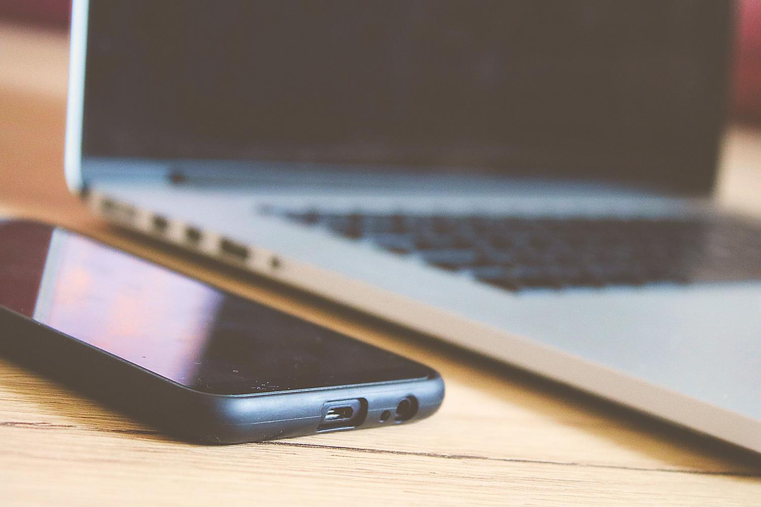 Smartphone Android y portátil sobre un escritorio, mostrando un entorno profesional de depuración de dispositivos.