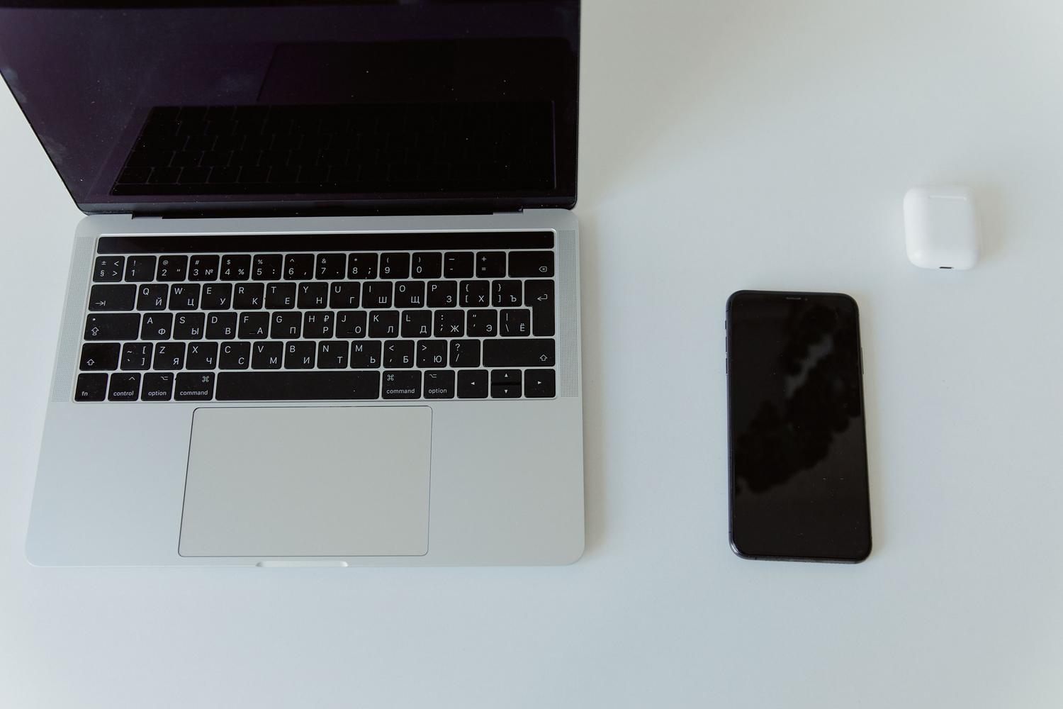 Vista cenital minimalista de un ordenador portátil y un smartphone, representando un ecosistema digital conectado.