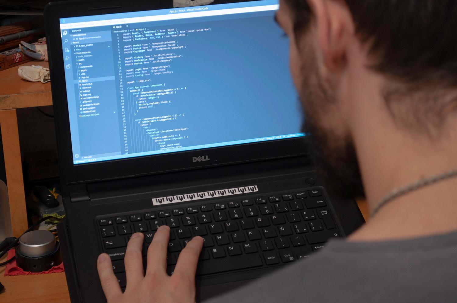 Hombre trabajando con código en un ordenador portátil en una oficina moderna