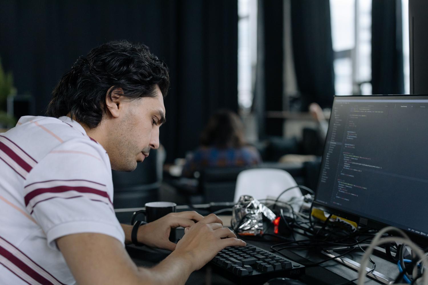 Programador concentrado escribiendo código en su estación de trabajo