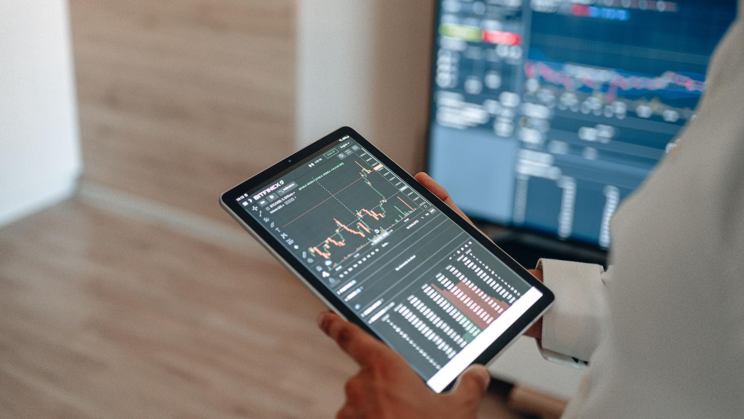 Profesional analizando tendencias del mercado financiero a través de una tablet en un entorno de trabajo moderno