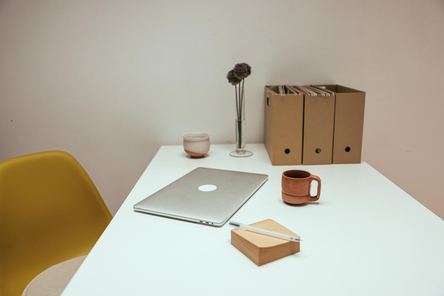 Espacio de trabajo minimalista y organizado con portátil y carpetas, representando un sistema optimizado y eficiente.