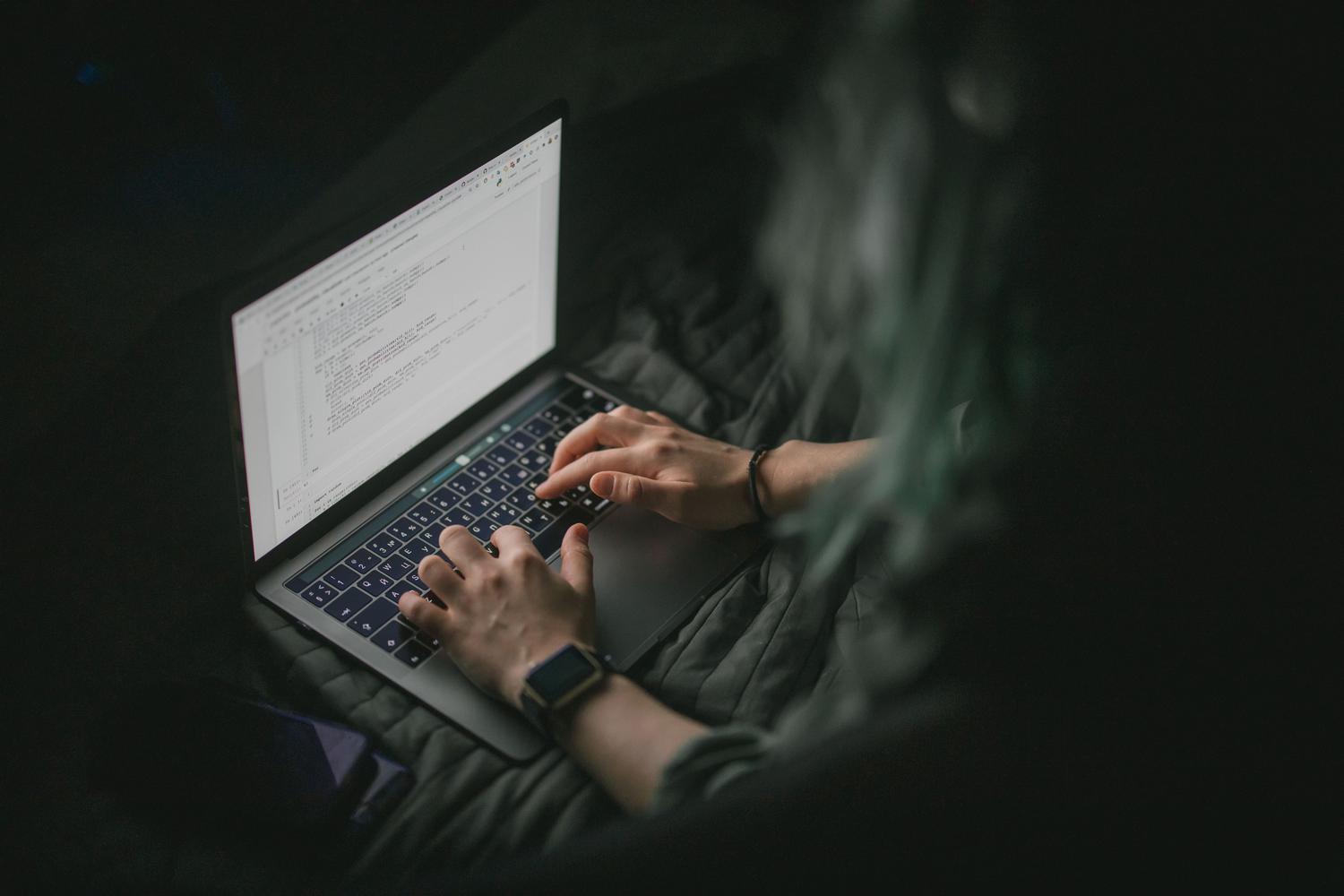 Primer plano de manos escribiendo código en un portátil, representando la creación de documentación de API y guías para desarrolladores.