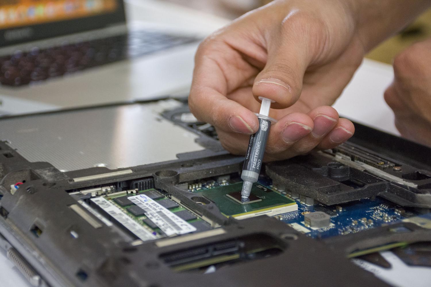 Mano de una persona aplicando pasta térmica con una jeringa sobre un chip de ordenador para mantenimiento