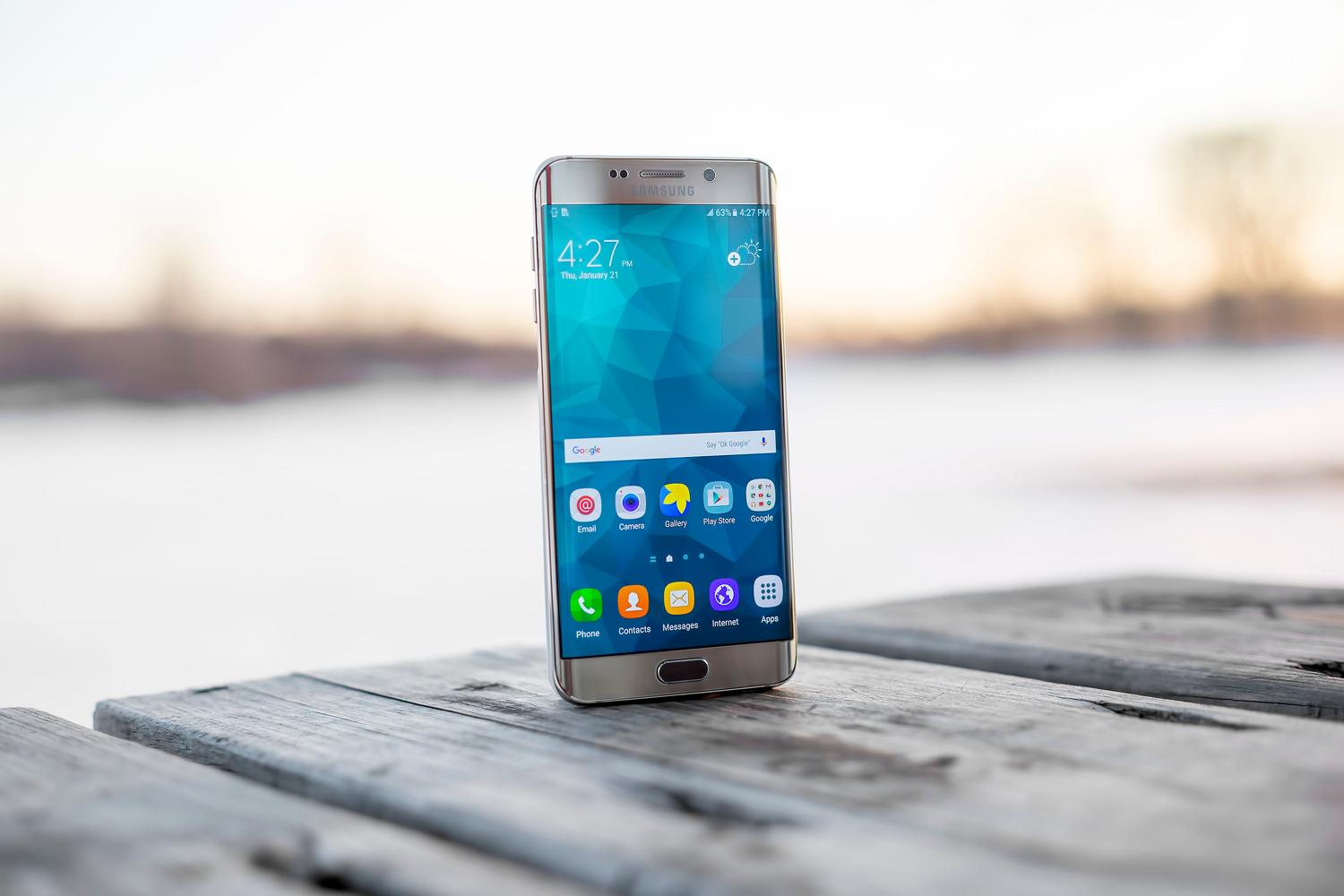 Smartphone Samsung elegante sobre una superficie de madera, representando un dispositivo Android optimizado y estable