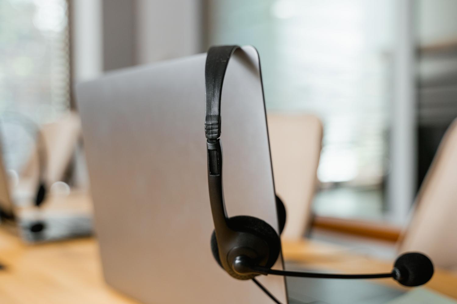 Auriculares profesionales Auriculares profesionales colgando de un portátil en una oficina, ilustrando el hardware de audio.
