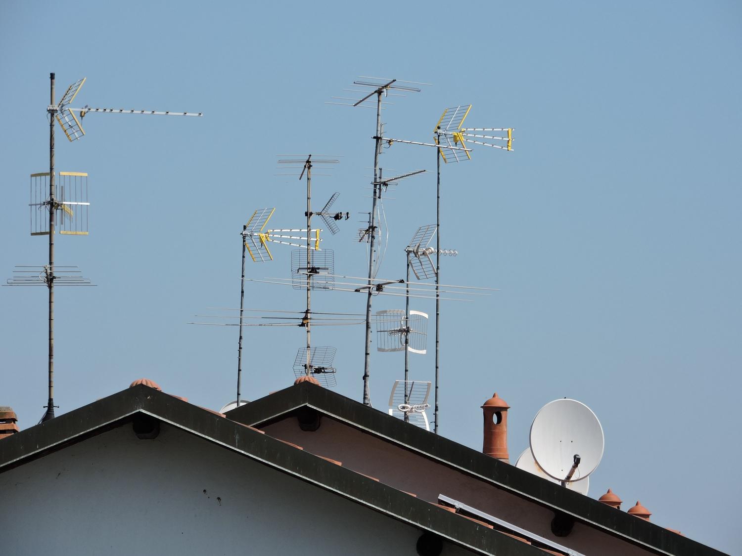 Diversas antenas de televisión instaladas en el tejado de una casa bajo un cielo despejado