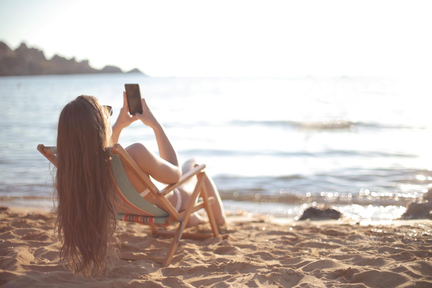 Mujer relajándose en una tumbona en la playa, simbolizando la desconexión digital durante las vacaciones.