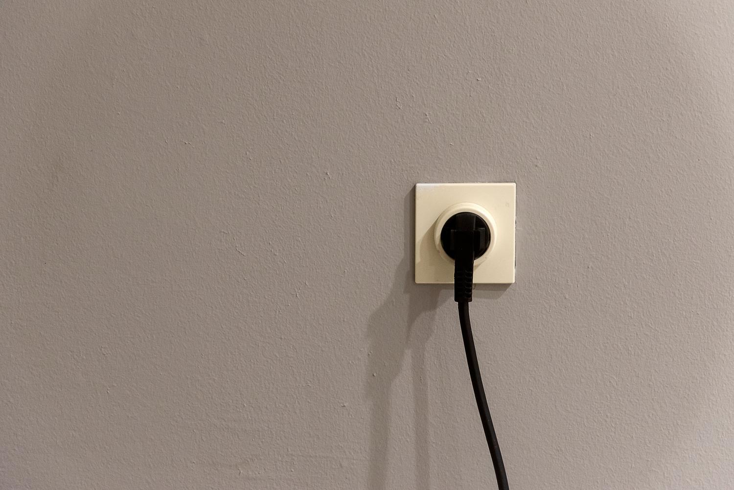 Enchufe eléctrico conectado a la pared, ilustrando el paso de reinicio eléctrico del televisor Enchufe eléctrico conectado a la pared, ilustrando el paso de reinicio eléctrico del televisor