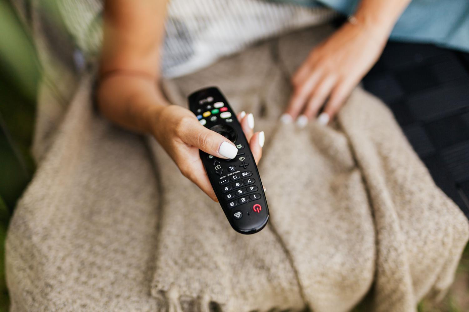 Persona relajada en el sofá con el mando de la tele en la mano.