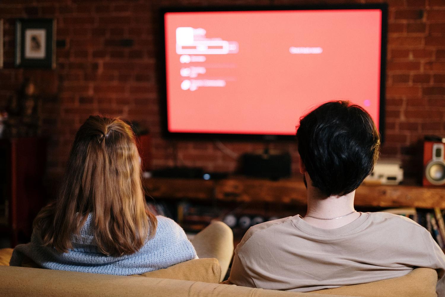 Pareja disfrutando de una película en el sofá, representando la solución final del problema de los subtítulos. Pareja disfrutando de una película en el sofá, representando la solución final del problema de los subtítulos.