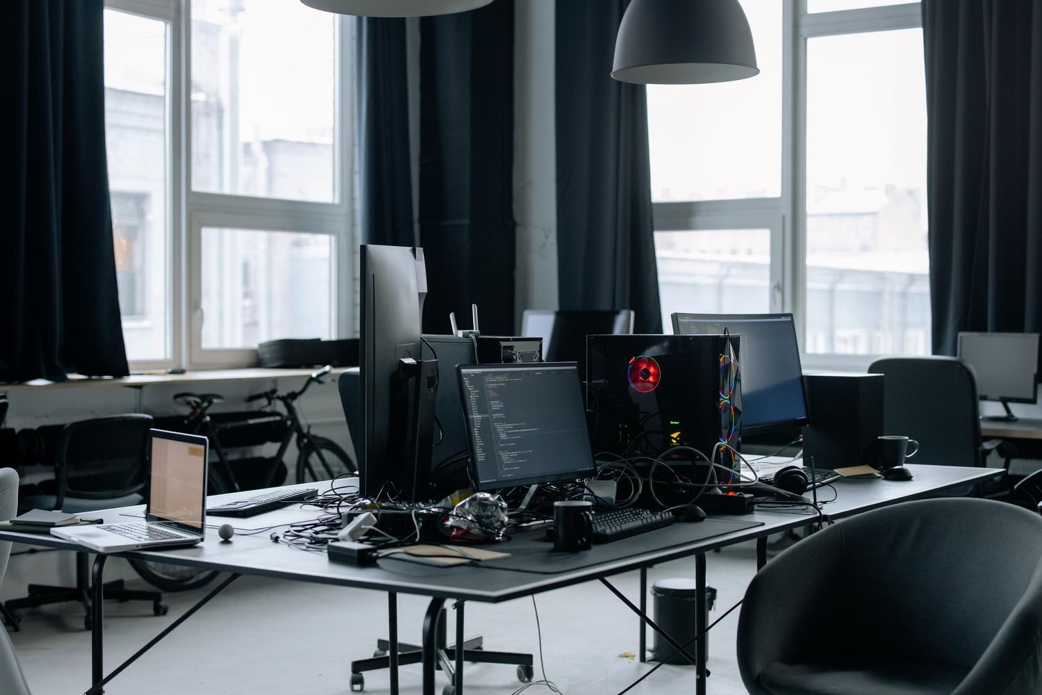 Espacio de trabajo tecnológico contemporáneo con pantallas de código y elementos de oficina en un entorno tech.