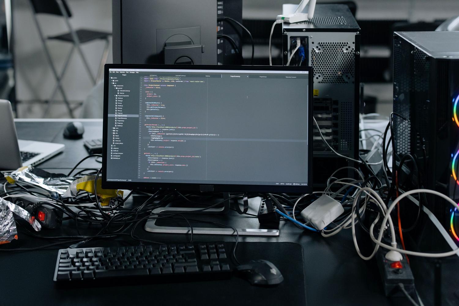 Estación de trabajo con monitor mostrando editor de HTML y código, representando la parte técnica del sistema.