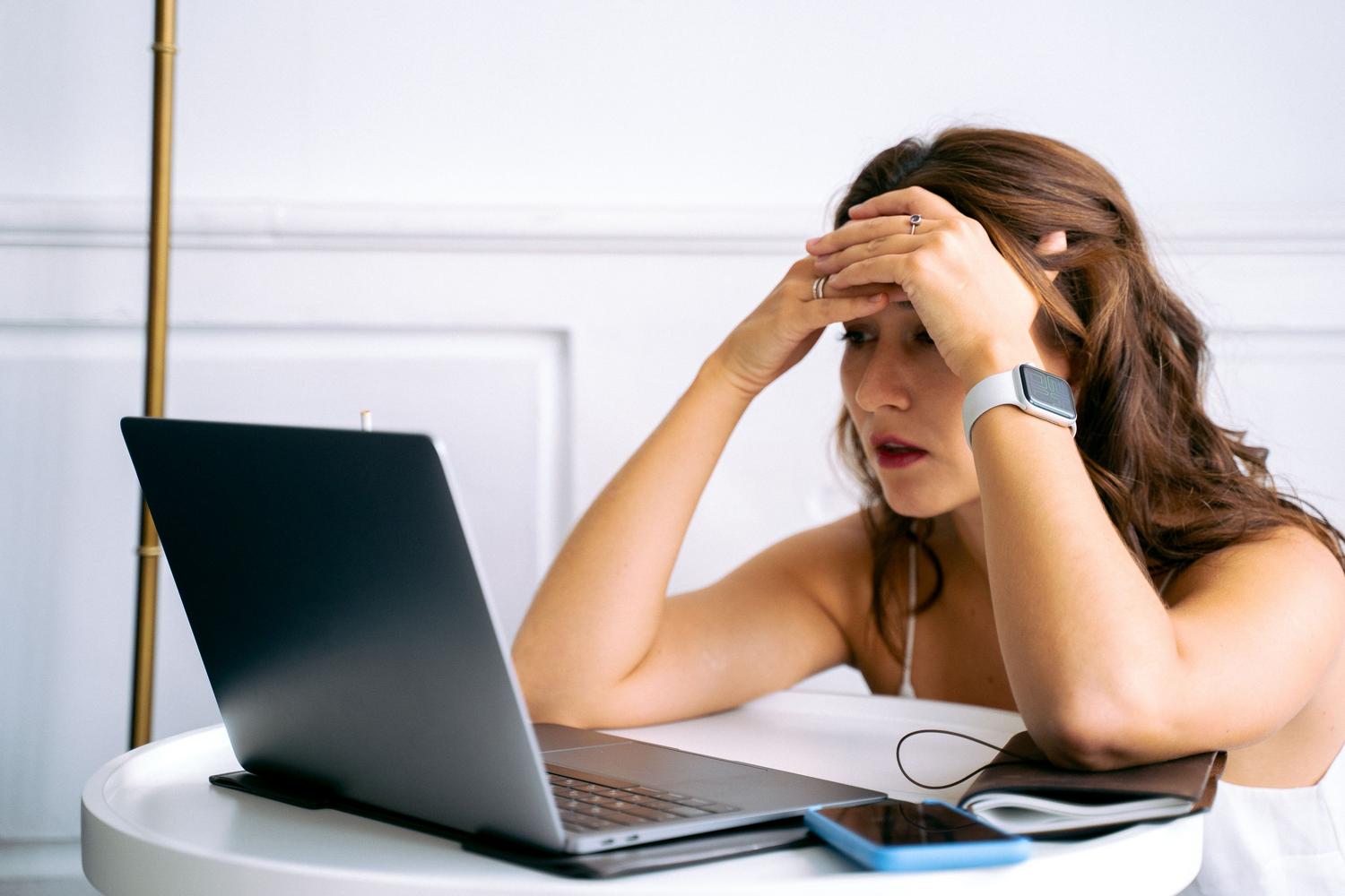 Mujer frustrada frente a su portátil al no detectar la red Wi-Fi.