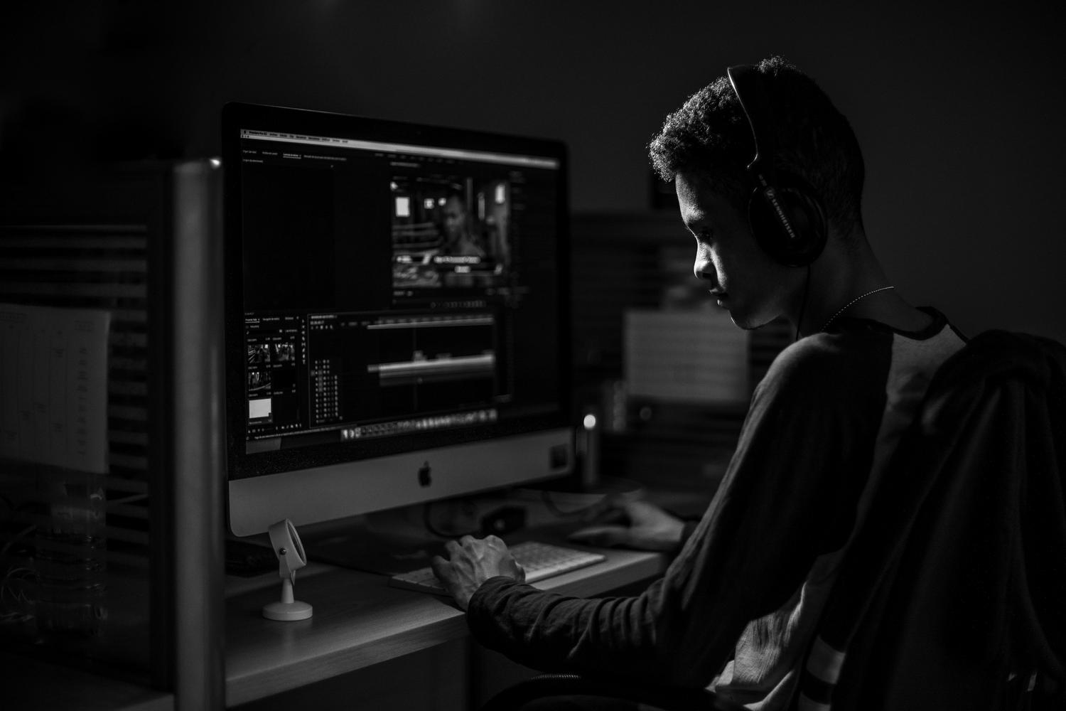 Creador de contenido editando video en un iMac dentro de un estudio con iluminación tenue