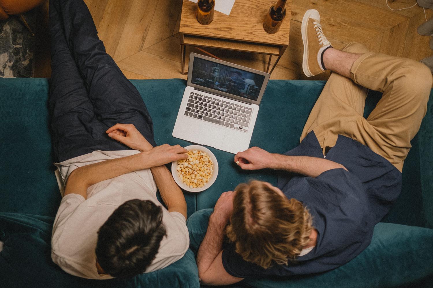 Dos personas viendo una película en un ordenador portátil desde un sofá, representando la experiencia de usuario