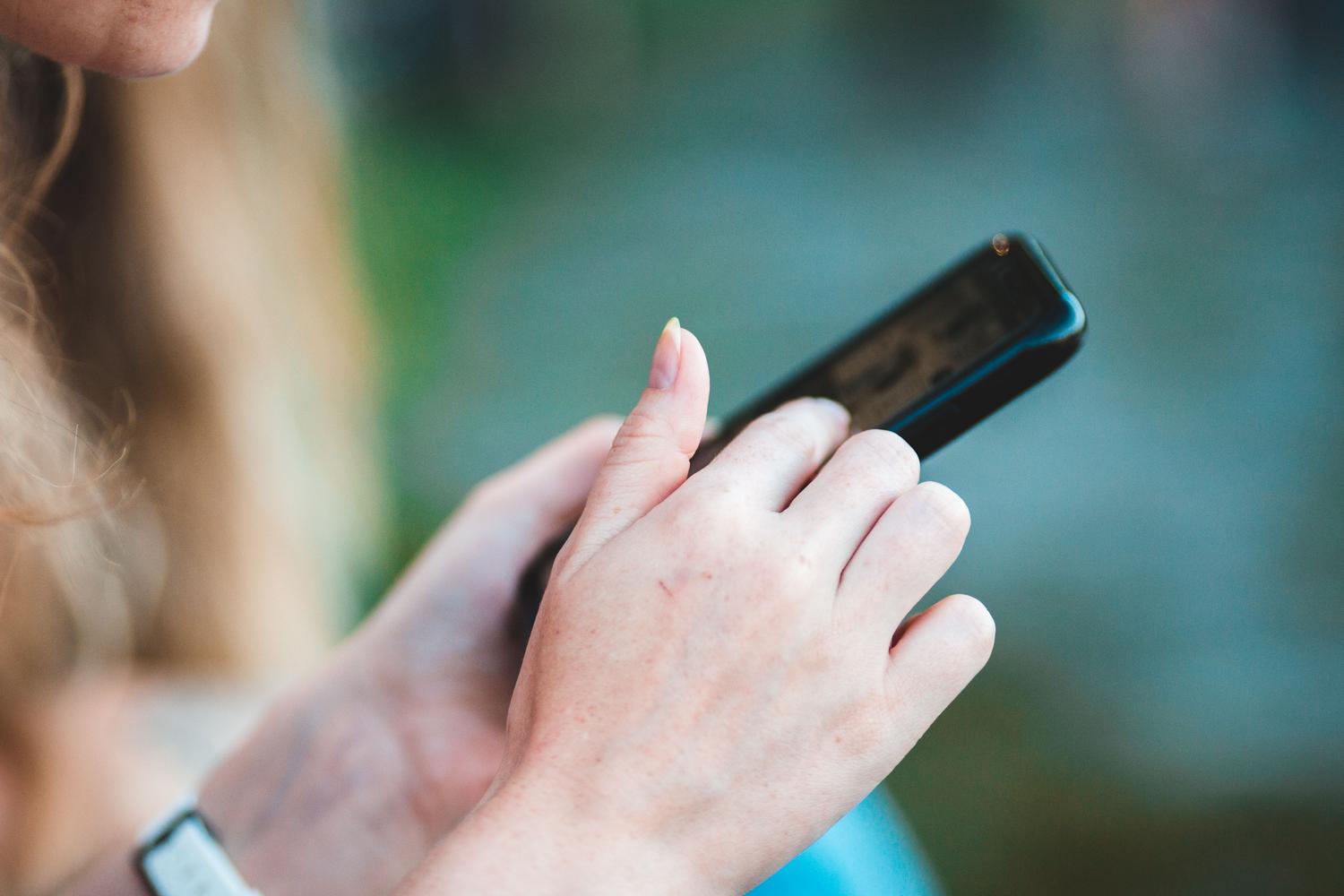 Close-up of hands using a smartphone, illustrating the AirPlay settings configuration on the Apple device.