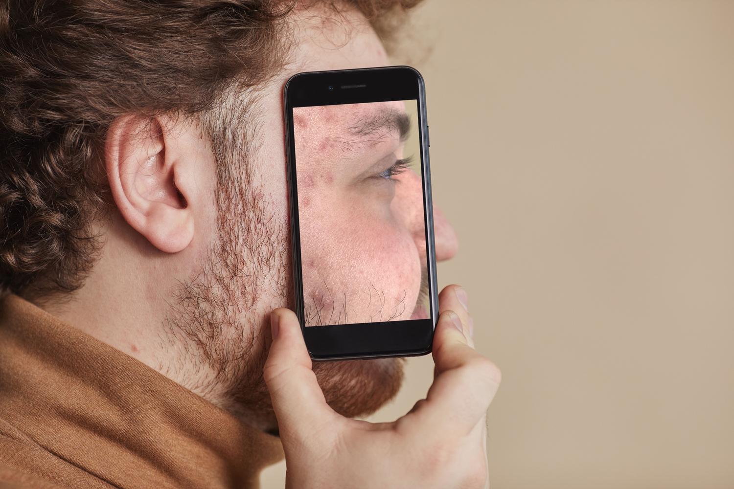 Hombre sosteniendo un smartphone frente a su rostro intentando desbloquear el dispositivo mediante reconocimiento facial