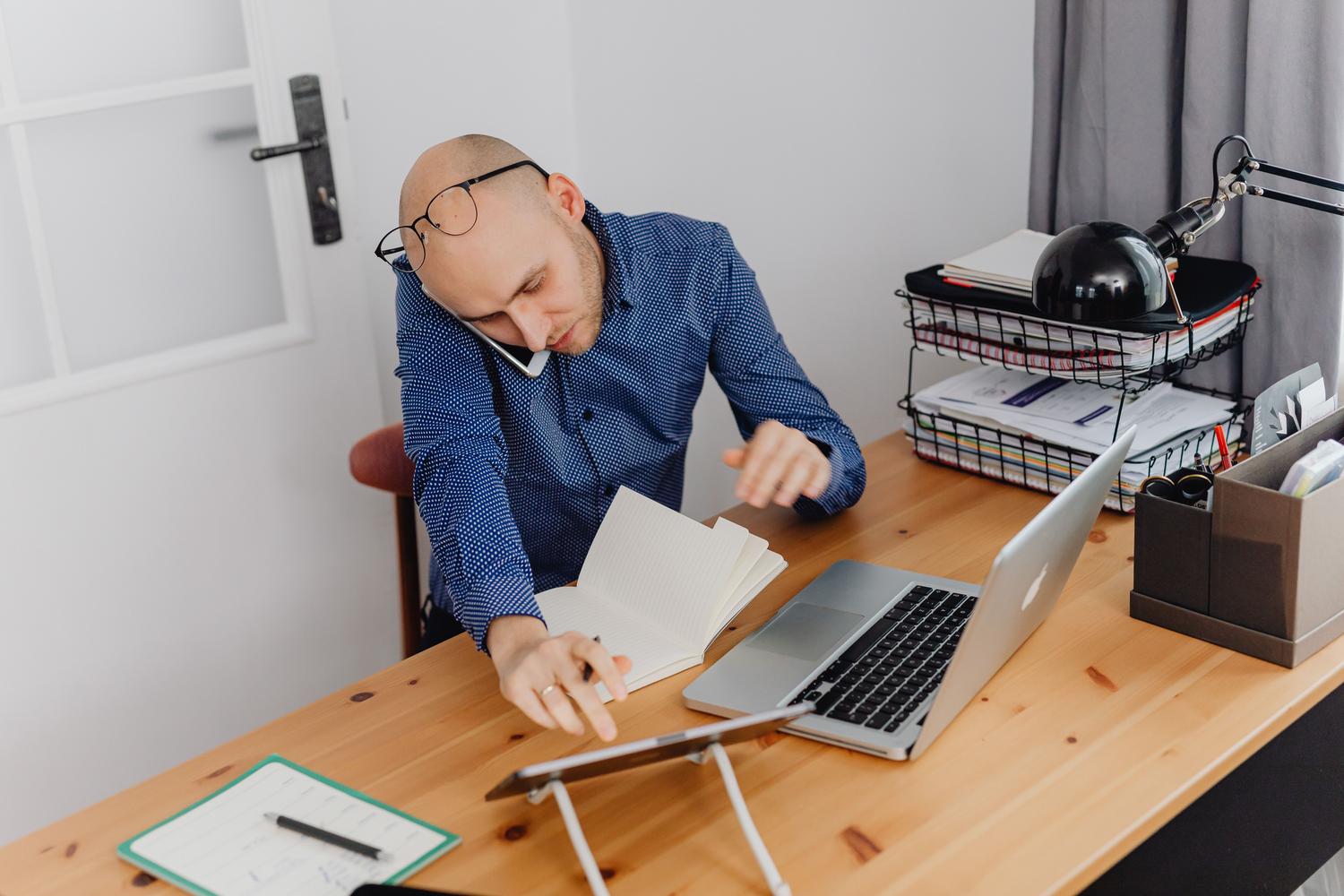 Hombre trabajando en su oficina en casa con portátil y notas, ideal para representar la separación entre perfiles de trabajo y ocio.