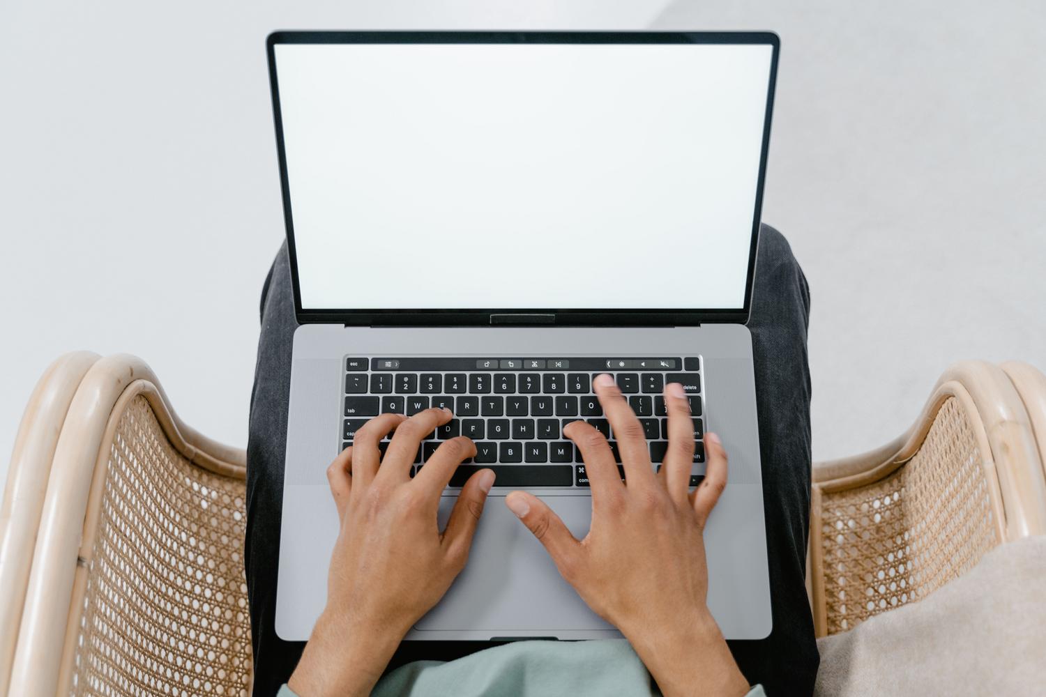 Vista superior de una persona utilizando un ordenador portátil en un entorno casual, preparando la descarga de Windows 11